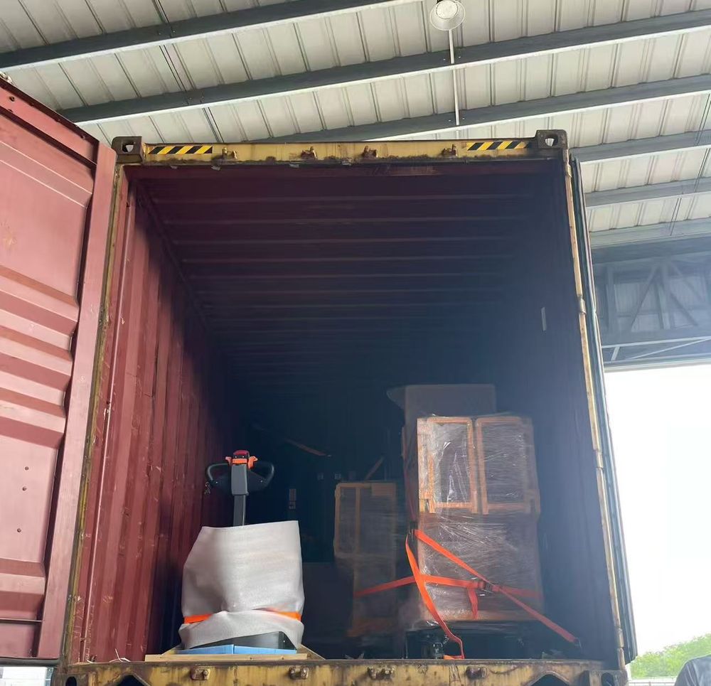 Electric pallet truck and a crated scissor lift strapped inside a container