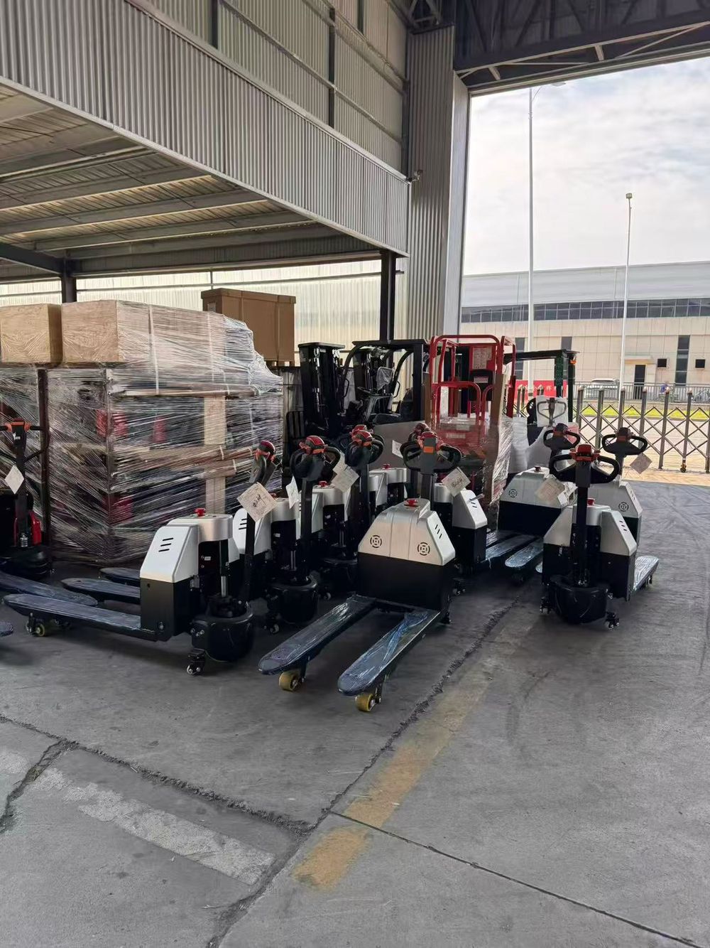 Silver and black electric pallet trucks waiting to be loaded at the Accelift factory